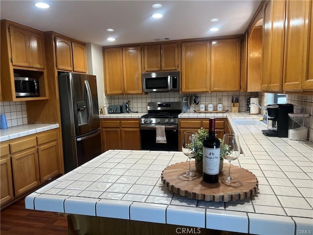 kitchen with tile counters, tasteful backsplash, visible vents, and appliances with stainless steel finishes