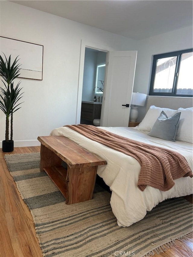 bedroom featuring wood finished floors and ensuite bathroom