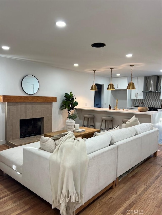 living area with recessed lighting, a brick fireplace, and dark wood-type flooring