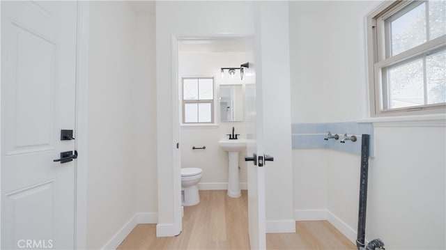 bathroom featuring a wealth of natural light, toilet, baseboards, and wood finished floors