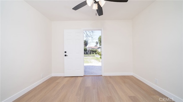 empty room featuring light wood-style flooring, a ceiling fan, and baseboards