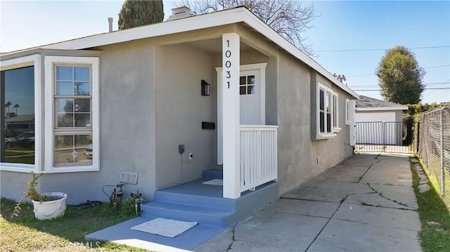 view of exterior entry featuring fence and stucco siding