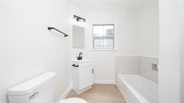 full bathroom featuring vanity, wood finished floors, baseboards, toilet, and a bath