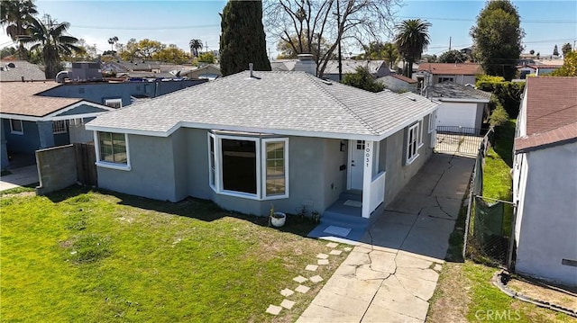 ranch-style home with stucco siding, driveway, fence, a front yard, and a shingled roof