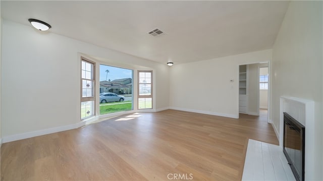 unfurnished living room featuring visible vents, baseboards, and light wood-style floors