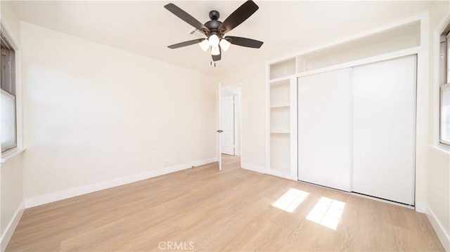 unfurnished bedroom featuring light wood finished floors, a closet, baseboards, and a ceiling fan