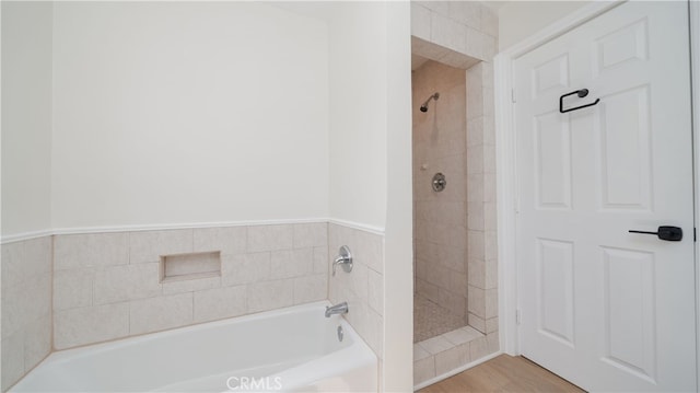 bathroom with a bath, tiled shower, and wood finished floors