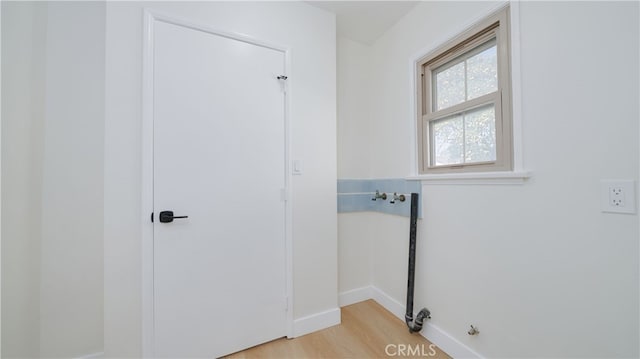 laundry area with laundry area, light wood-type flooring, and baseboards