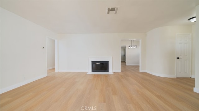 unfurnished living room featuring light wood-type flooring, visible vents, and baseboards