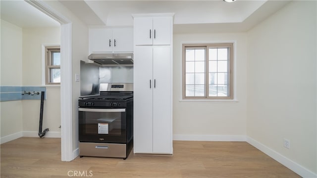 kitchen featuring light wood-type flooring, under cabinet range hood, baseboards, white cabinets, and gas range