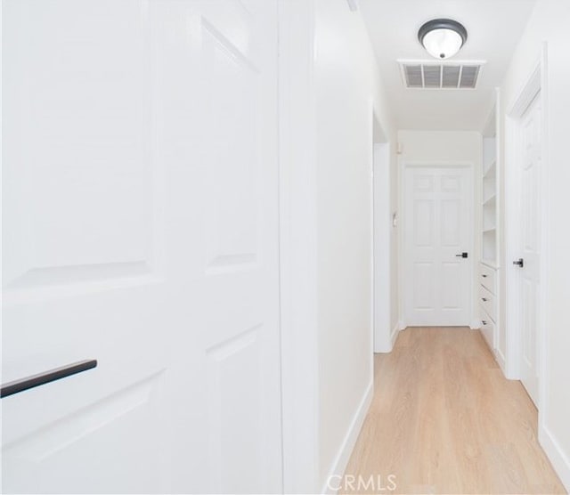 hall with visible vents, baseboards, and light wood-style floors