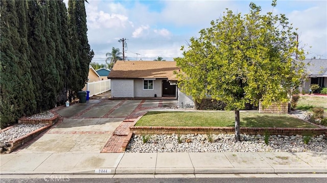 view of front of property with stucco siding, driveway, a front lawn, and fence