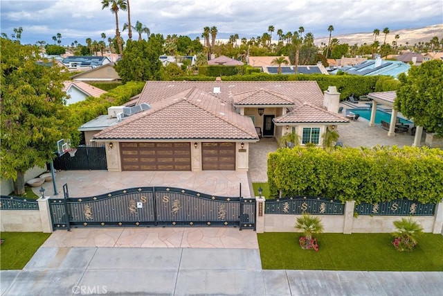 mediterranean / spanish-style house featuring a gate, stucco siding, a garage, a fenced front yard, and a tile roof