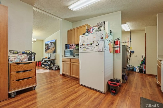 22292 N Tuolumne Rd, Twain Harte, CA 95383 - kitchen with stainless steel microwave, light wood-type flooring, light countertops, freestanding refrigerator, and a textured ceiling