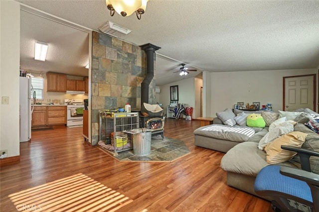 22292 N Tuolumne Rd, Twain Harte, CA 95383 - living room featuring a ceiling fan, wood finished floors, lofted ceiling, a wood stove, and a textured ceiling