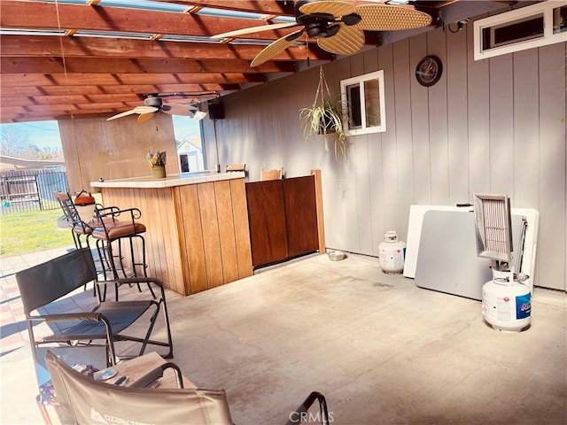 bar with wooden walls, concrete flooring, and ceiling fan