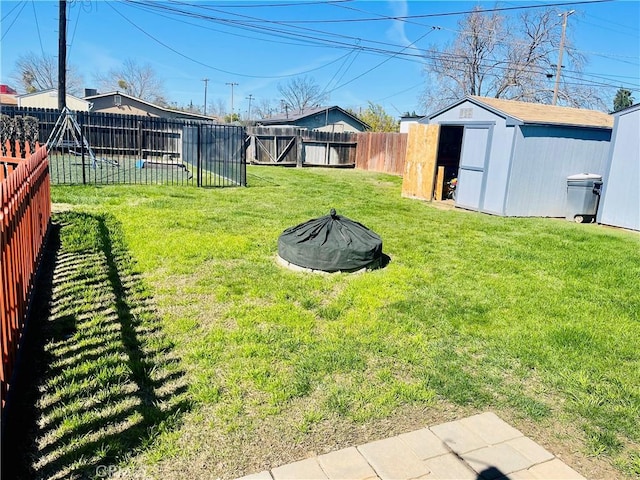 view of yard featuring an outbuilding, a fire pit, a storage shed, and a fenced backyard