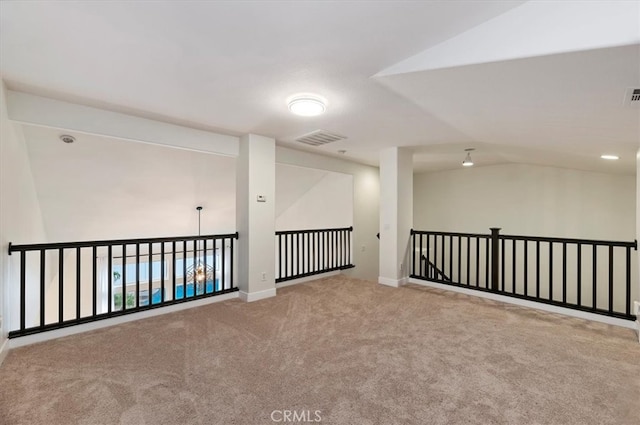 carpeted empty room with visible vents, vaulted ceiling, and baseboards
