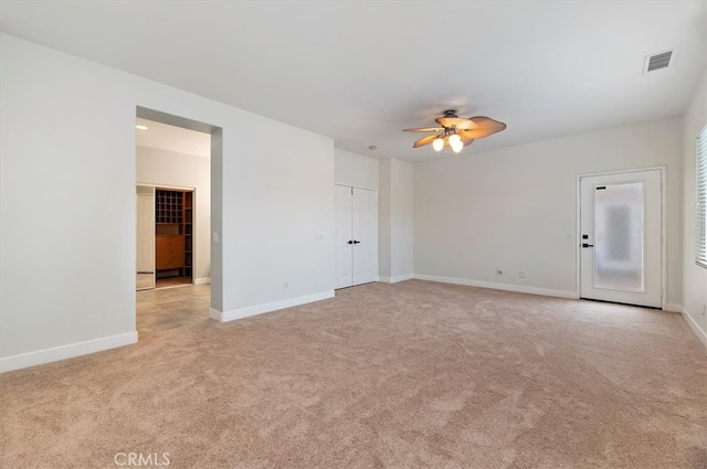 spare room featuring visible vents, light carpet, baseboards, and a ceiling fan