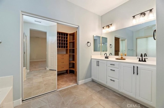 bathroom with double vanity, visible vents, a spacious closet, and a sink