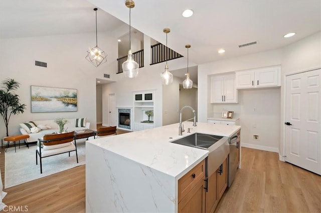 kitchen featuring visible vents, light wood-style flooring, a sink, stainless steel dishwasher, and open floor plan