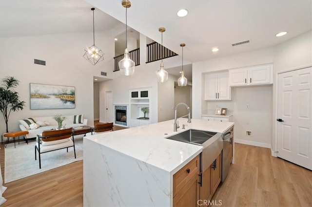 kitchen with visible vents, stainless steel dishwasher, light wood-style flooring, and a sink