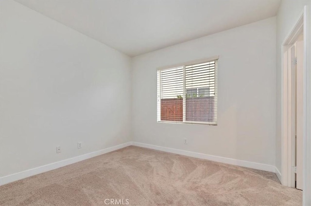 spare room featuring baseboards and light carpet