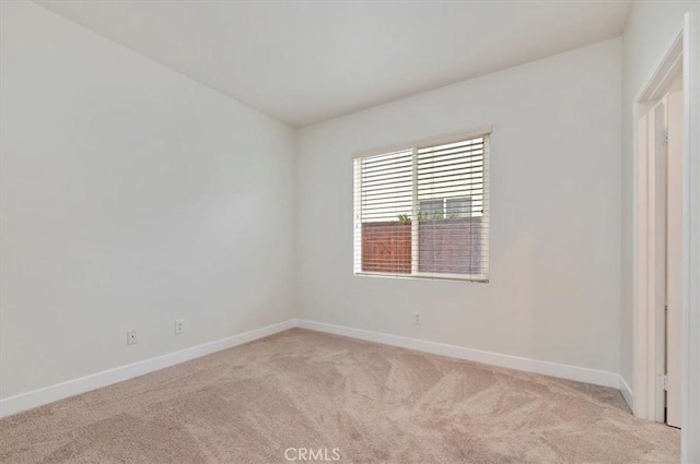 spare room with baseboards and light carpet