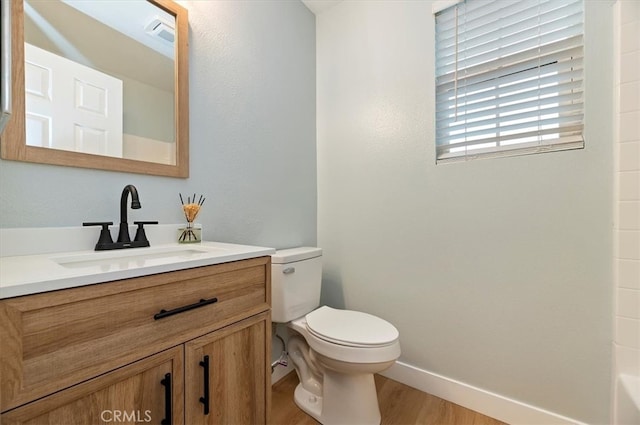 bathroom with baseboards, wood finished floors, toilet, and vanity