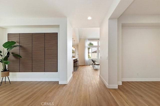 hall featuring baseboards, recessed lighting, and light wood-style flooring