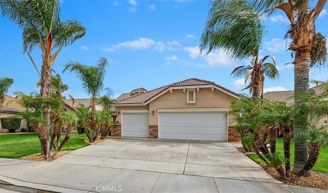 view of front of property featuring concrete driveway, a tiled roof, a front yard, an attached garage, and stucco siding