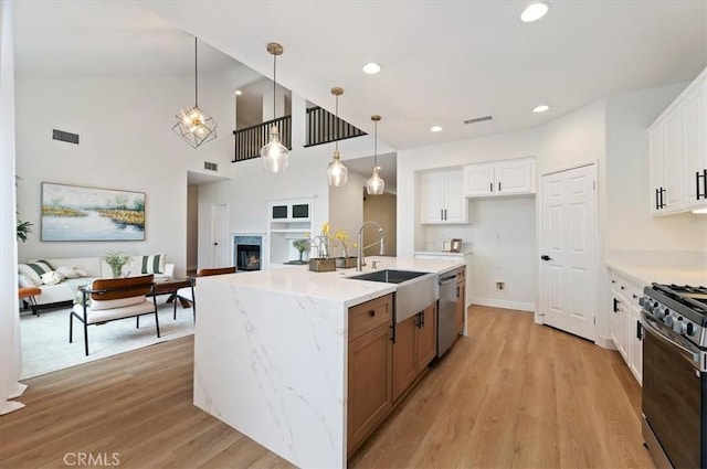 kitchen featuring visible vents, open floor plan, stainless steel appliances, white cabinetry, and a sink