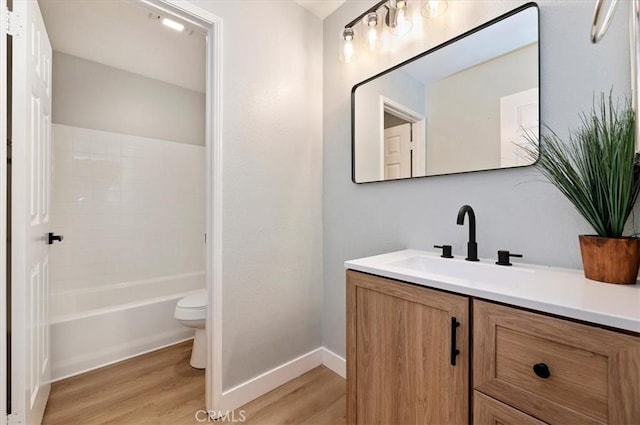 bathroom featuring baseboards, toilet, shower / tub combination, wood finished floors, and vanity