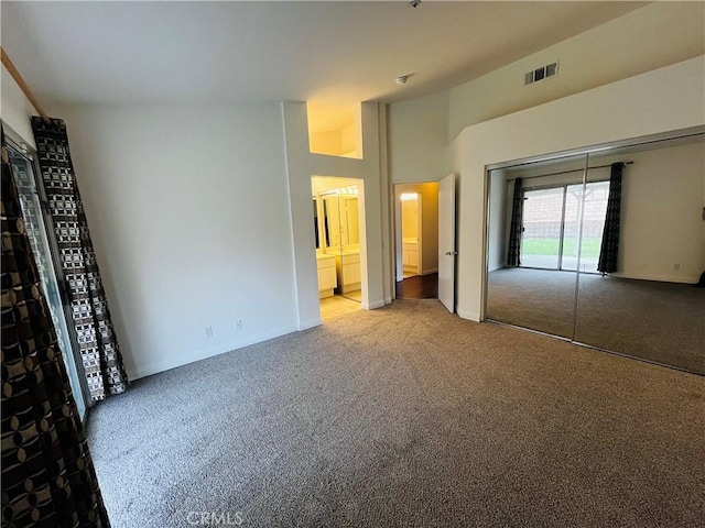 unfurnished bedroom featuring visible vents, baseboards, vaulted ceiling, carpet floors, and ensuite bath