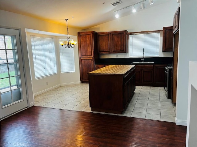 kitchen featuring visible vents, butcher block countertops, vaulted ceiling, range with gas stovetop, and a sink