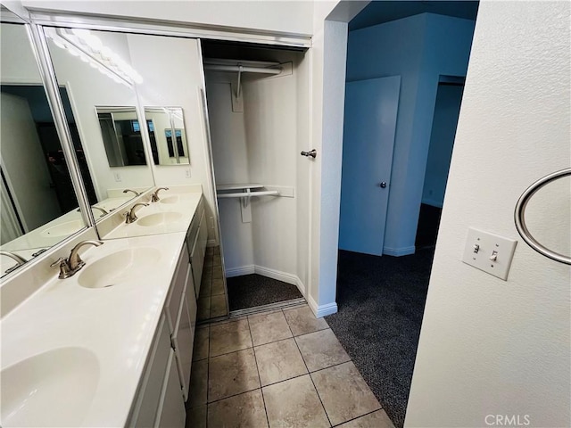 bathroom with tile patterned floors, double vanity, baseboards, and a sink