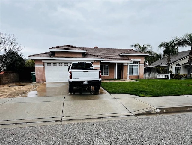 view of front of house with a front yard, an attached garage, stucco siding, concrete driveway, and a tiled roof