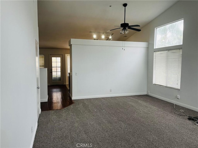 unfurnished room with track lighting, baseboards, dark carpet, and ceiling fan