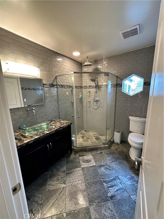 full bathroom featuring vanity, visible vents, a shower stall, tile walls, and toilet