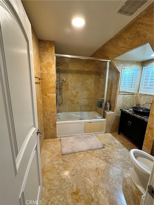 bathroom featuring vanity, tile walls, visible vents, and enclosed tub / shower combo