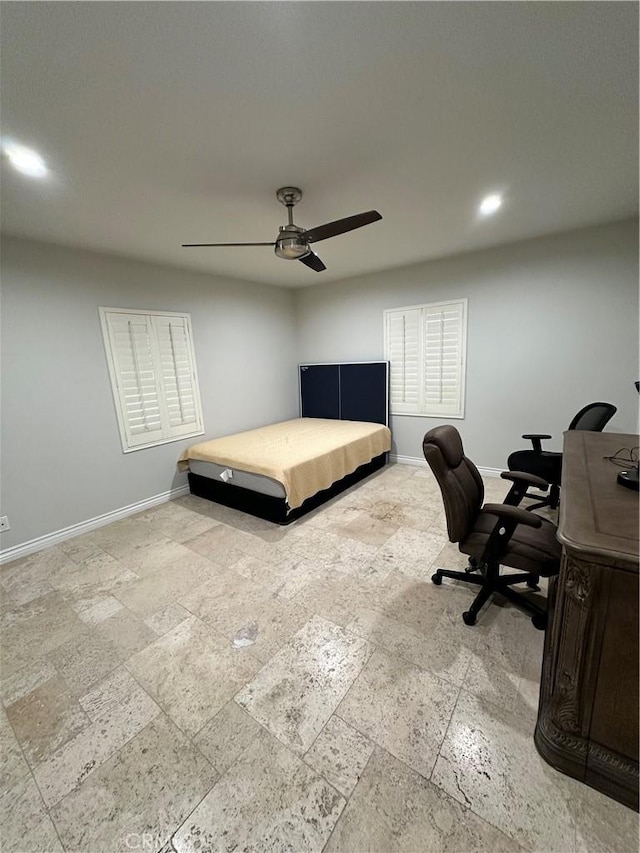 bedroom with stone tile floors, a ceiling fan, and baseboards