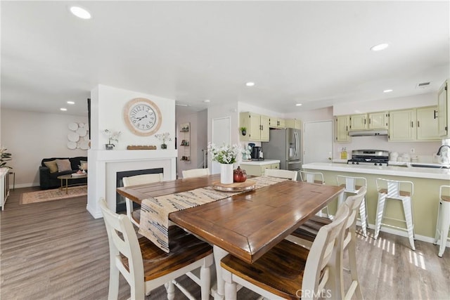 dining room featuring a fireplace, light wood-style floors, and recessed lighting