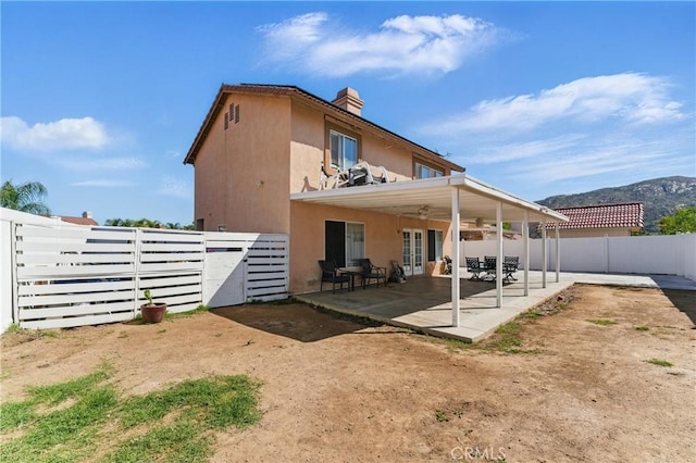 rear view of property featuring a fenced backyard, a chimney, stucco siding, and a patio