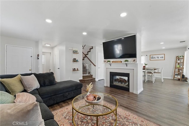 living area with recessed lighting, baseboards, stairs, and wood finished floors