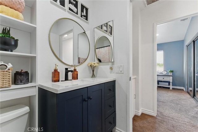 bathroom with toilet, vanity, baseboards, and visible vents