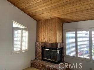 unfurnished living room with a wealth of natural light, lofted ceiling, a brick fireplace, and wooden ceiling