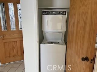 washroom with laundry area, light tile patterned floors, and stacked washer and clothes dryer