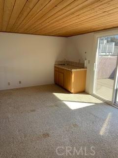 carpeted empty room with wood ceiling and a sink