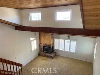 unfurnished living room with carpet, a towering ceiling, wood ceiling, and a wealth of natural light