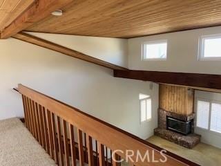 stairs with beamed ceiling, wooden ceiling, and a brick fireplace